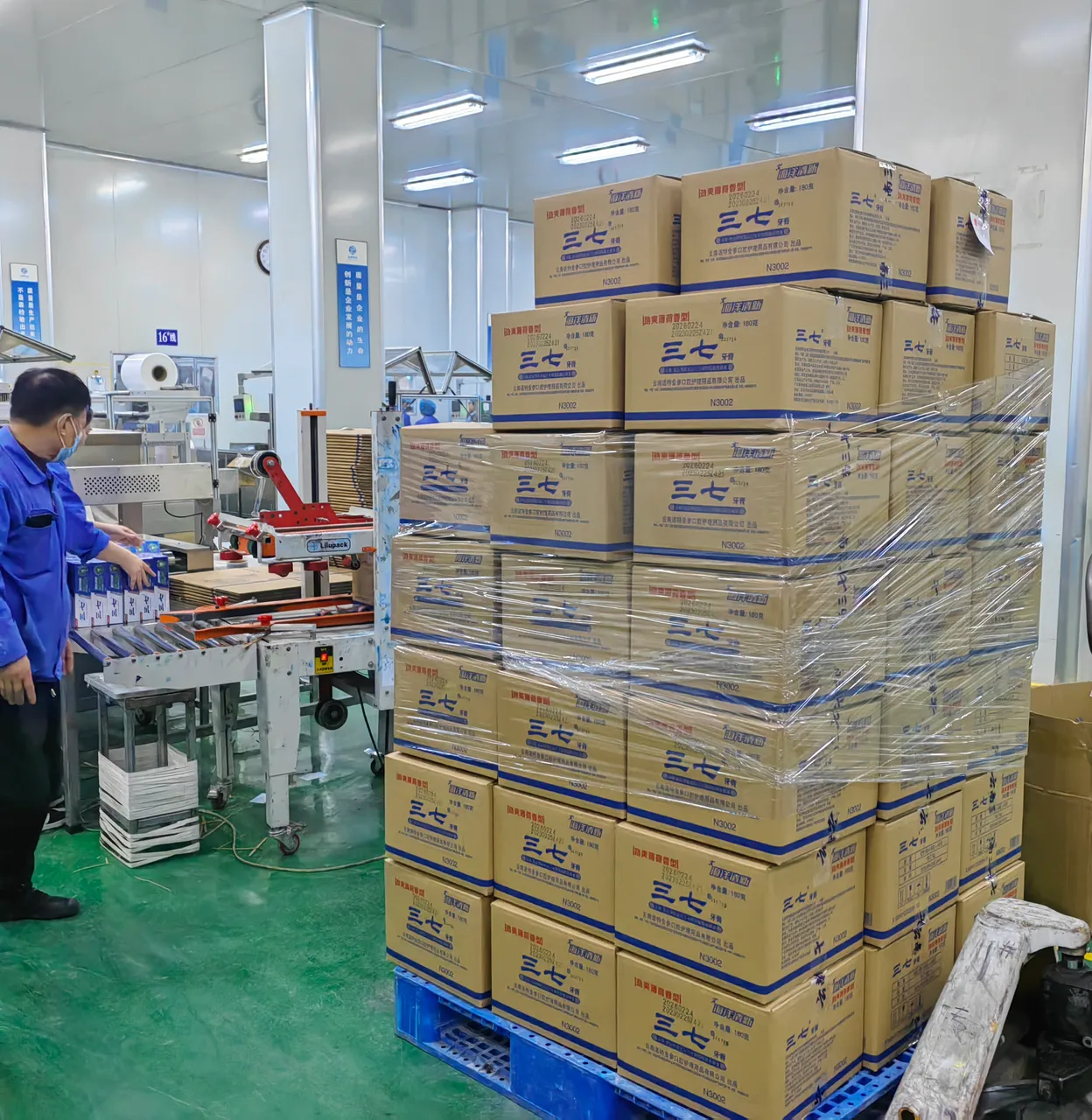 Worker sealing finished toothpaste cartons on the production line