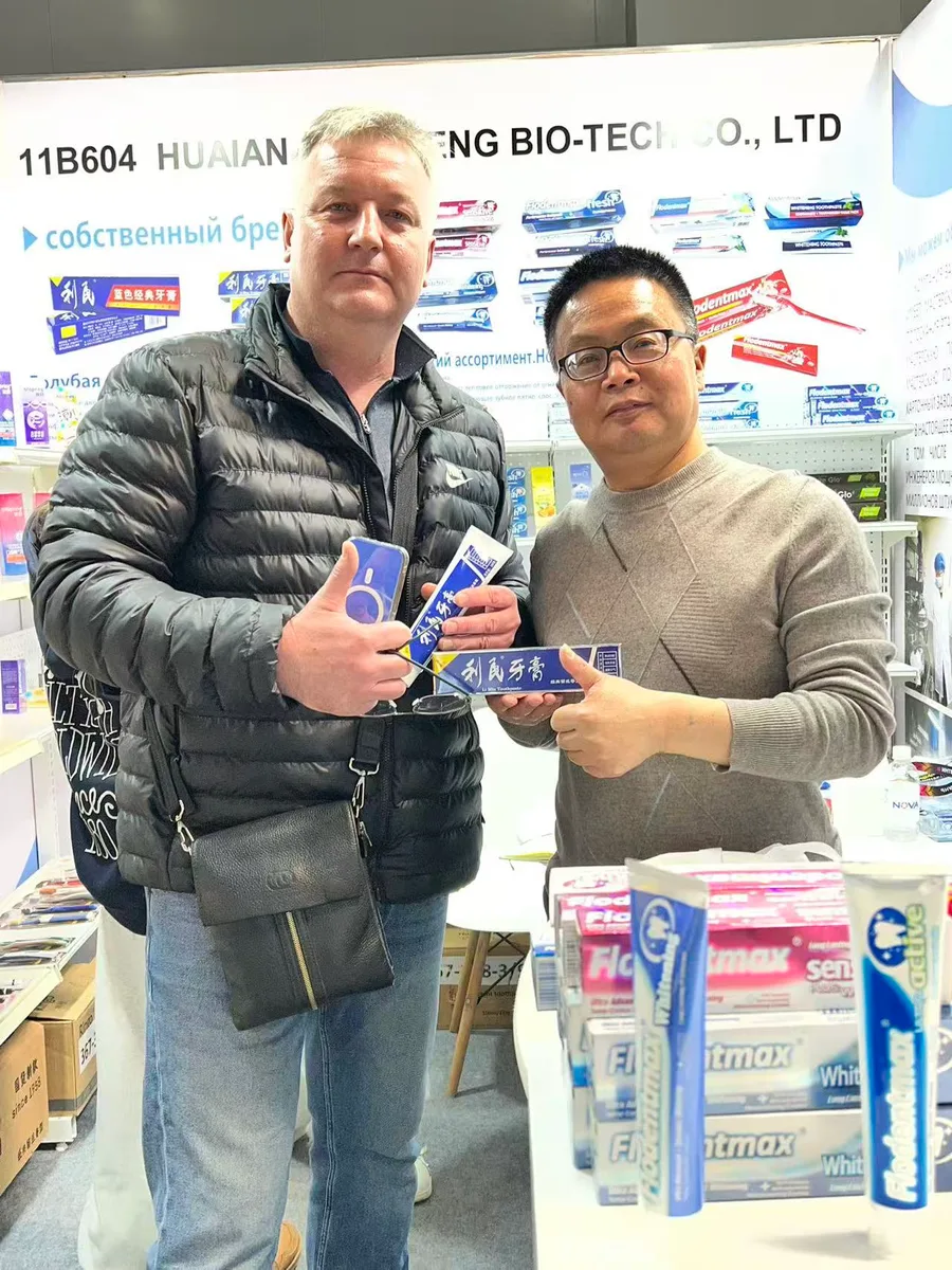 A Russian buyer and Zongheng sales representative holding a box of Limin toothpaste at the booth