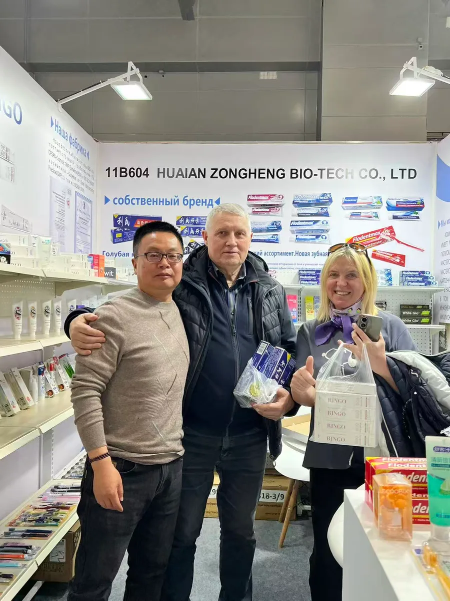 A Russian couple with shopping bags giving a thumbs-up next to a Zongheng sales representative at the booth